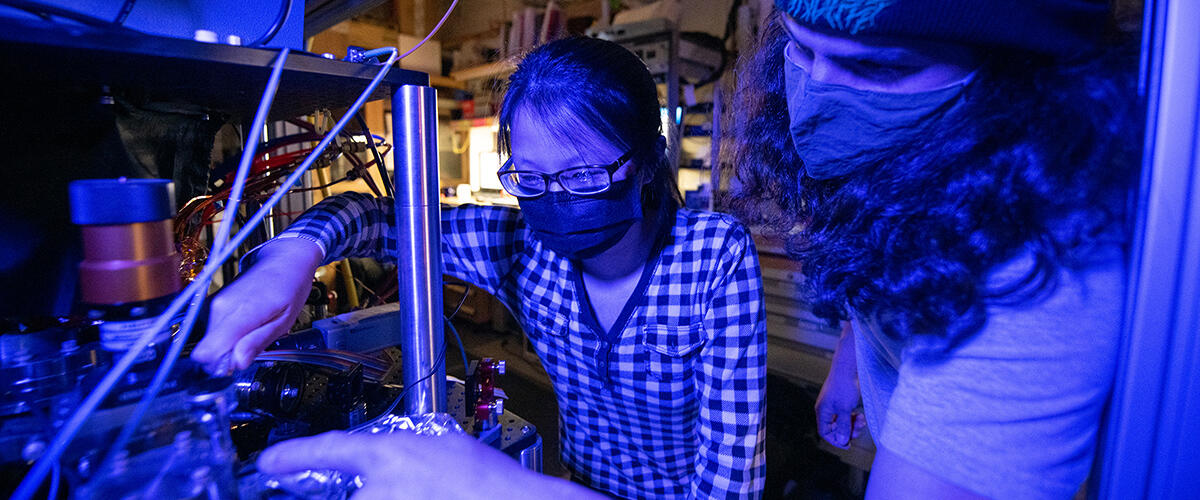 Two students working in a laser lab with blue lighting