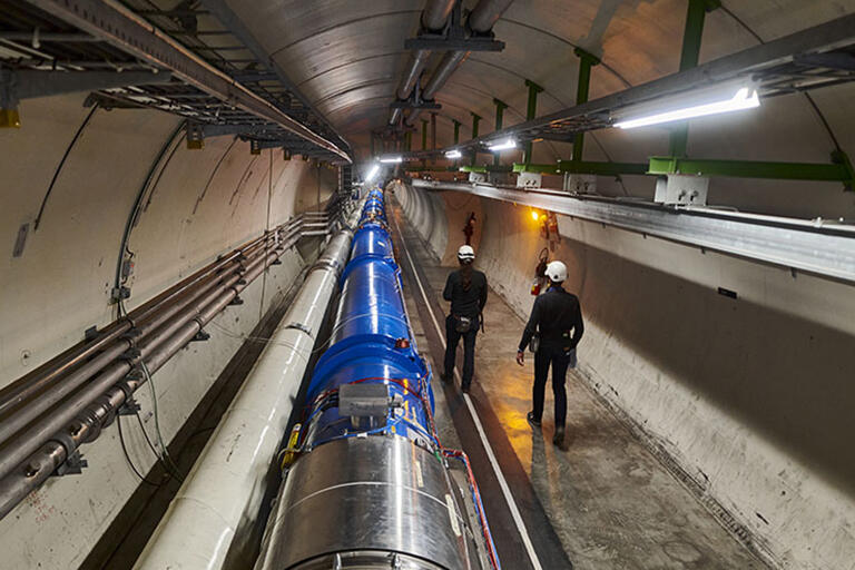 Two men walking through a tunnel at the Large Hadron Collider
