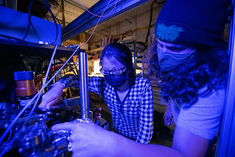 Undergrad student working on laser equipment with graduate student in the lab 