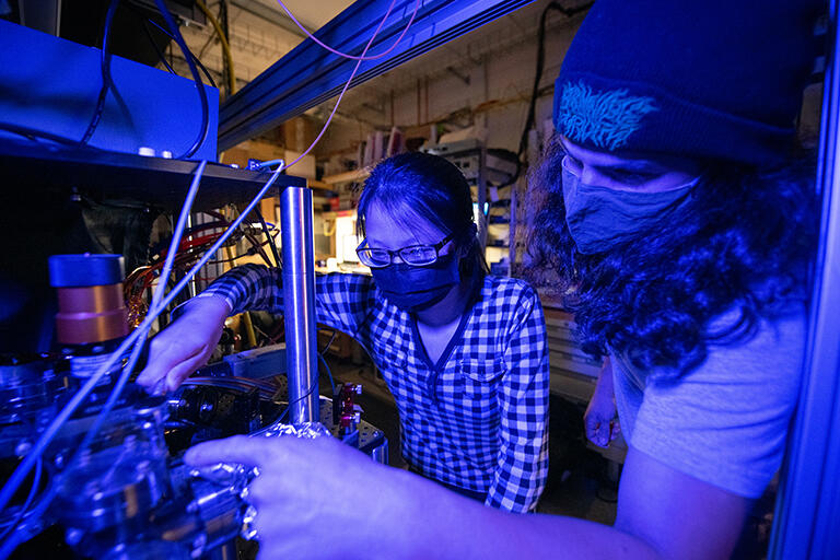 Undergrad student working on laser equipment with graduate student in the lab