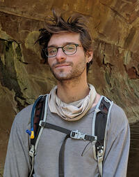 Photo of Alex in a cave wearing climbing gear