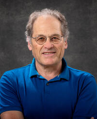 Photo of Professor Joe Orenstein in a blue shirt on a dark background